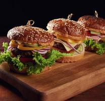 delicious burgers with fried beef cutlet, tomato, lettuce and onions, crispy white wheat flour bun with sesame seeds photo