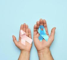 female hand holding pink ribbon bow, male hand holding blue ribbon photo