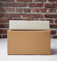caja rectangular hecha de cartón ondulado marrón sobre un fondo de pared de ladrillo marrón foto