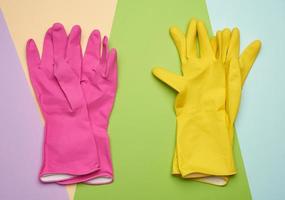 two pairs of protective rubber gloves on a colored background photo