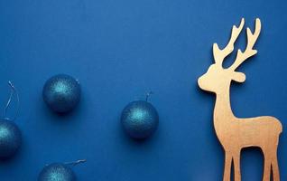 blue shiny christmas balls for the tree and carved wooden deer on a blue background photo