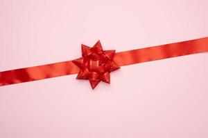 red silk ribbon and big bow on a pink background, gift wrap photo