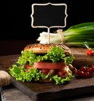 cheeseburger with minced meat, green lettuce and ketchup on a wooden brown kitchen board photo