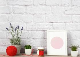 empty photo frame, succulents to a white ceramic pot and a red ball with woolen thread