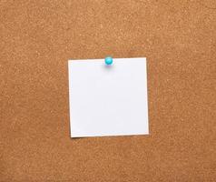 blank square white sheet of paper attached with blue button on a brown background photo