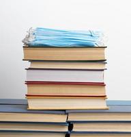 stack of various books and disposable medical masks on a white background, concept of visiting libraries photo