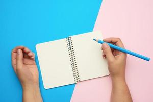 two male hands holding open notepad with empty white sheets photo
