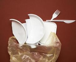 used plastic dishes, pieces of plastic and a white plastic bag on a brown background photo