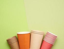 brown, red paper disposable cups on a green background, flat lay photo