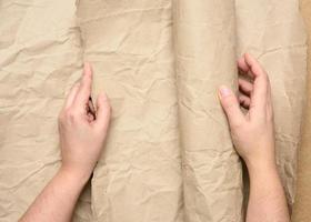 two female hands hold rolled brown paper photo