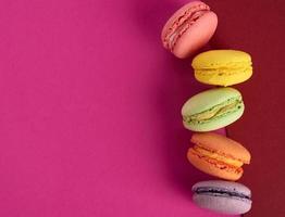 tortas de harina de almendras macarons horneadas multicolores sobre un fondo rojo foto