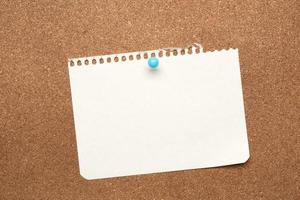 hoja de papel blanca en blanco adjunta con un botón azul sobre un fondo marrón foto