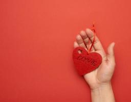 female hand holding red heart on red background photo