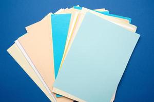pila de hojas de papel multicolor sobre un fondo azul foto