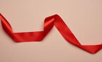 twisted red silk ribbon on a beige background photo