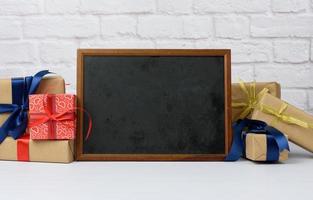 empty wood frame and stack of various gift boxes on white brick background photo