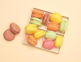 wooden box and baked multi-colored macarons cookies on a beige background photo