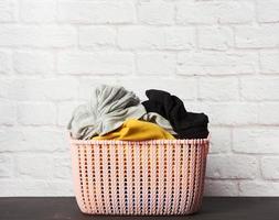 full pink plastic round laundry basket with white brick wall background