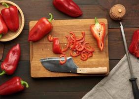 pimiento rojo en rodajas sobre una tabla de madera, mesa de madera marrón foto