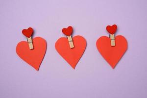 red paper heart pinned on a wooden clothespin, purple background photo