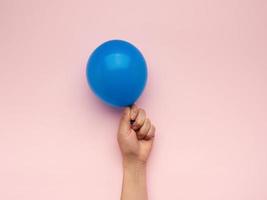 mano femenina sosteniendo un globo de aire azul inflado foto