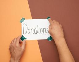 two male hands hold a sheet of paper with the inscription donations photo