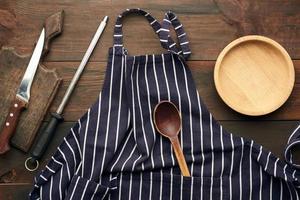 blue textile kitchen apron with white stripes and kitchen utensils, top view photo