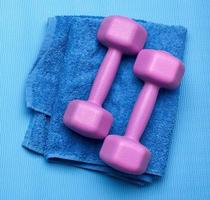 pair of purple dumbbells and blue towel on a blue background photo