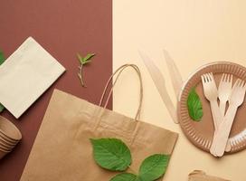 disposable paper utensils from brown craft paper and recycled materials on a brown background photo