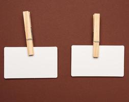 empty white paper rectangular business cards with wooden clothespins on a brown background photo