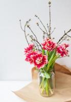 A beautiful spring bouquet of tulips stands in a vase along with spring branches. Surprise concept, birthday. Vertical photo, place for an inscription. photo