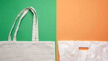 Beige textile eco-friendly bag and white plastic bag, flat lay photo