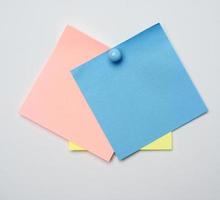 stack of colorful stickers pinned by blue button on white background photo