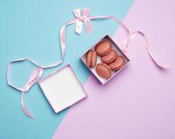 baked round multicolored macarons in square boxes on a colored pastel background photo