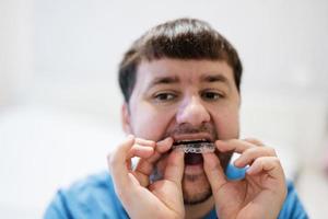 aparato de ortodoncia móvil para la corrección dental. hombre con entrenador de ortodoncia de silicona o alineador de aparatos ortopédicos invisibles. foto