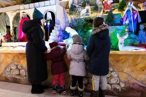 Mother with three children visit Christmas nativity crib scene in church. photo