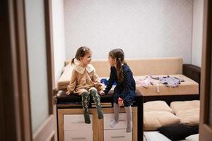 Two sisters sit on the sofa and tell and share girlish secrets with each other. photo