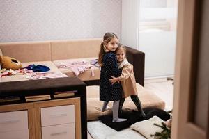 Two sisters at home on the sofa hugging tightly together. photo