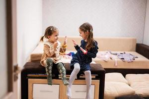 Two sisters are sitting on a couch and give each other high fives. photo