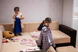 dos hermanas están eligiendo ropa del armario en casa en el sofá. foto