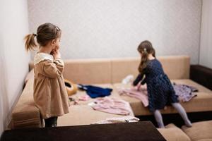 dos hermanas están eligiendo ropa del armario en casa en el sofá. foto