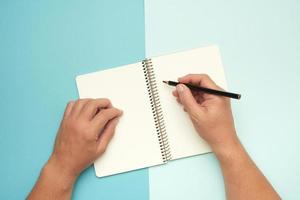 two male hands holding open notepad with empty white sheets photo