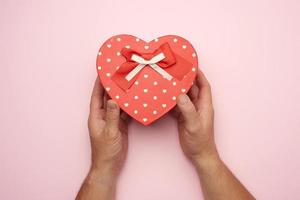 male hand holding a red cardboard box with a bow photo