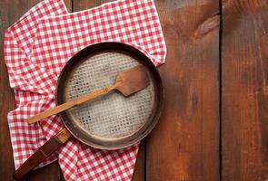 empty round frying pan with handle on brown wooden table photo