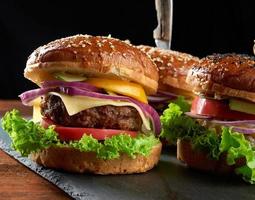 delicious burgers with fried beef cutlet, tomato, lettuce and onions, crispy white wheat flour bun with sesame seeds photo