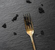 fresh grainy black paddlefish caviar in metal fork on a black background photo