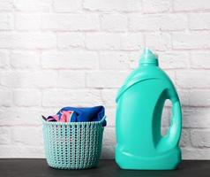 cesta de ropa redonda de plástico y botella verde con polvo líquido para ropa foto