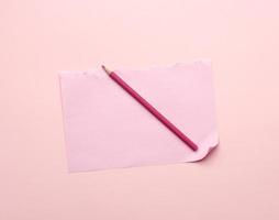 hoja de papel rota rosa en blanco de un cuaderno y un lápiz de madera foto