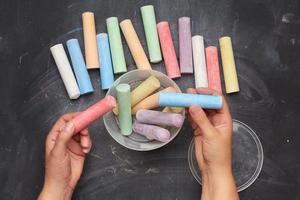 multicolored chalk in a plastic bucket on a black background photo