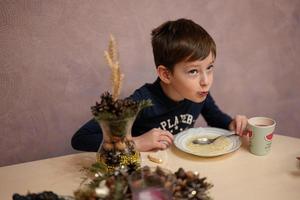 Boy has dinner in kitchen, eat bouillon. photo